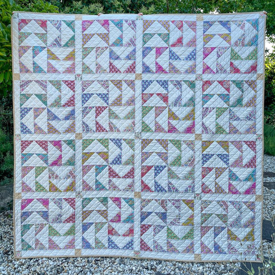 Dutchman's Puzzle Quilt in the garden. Quilt is made of Flying Geese Blocks with the flying geese seeming to fly in circles in each block.
