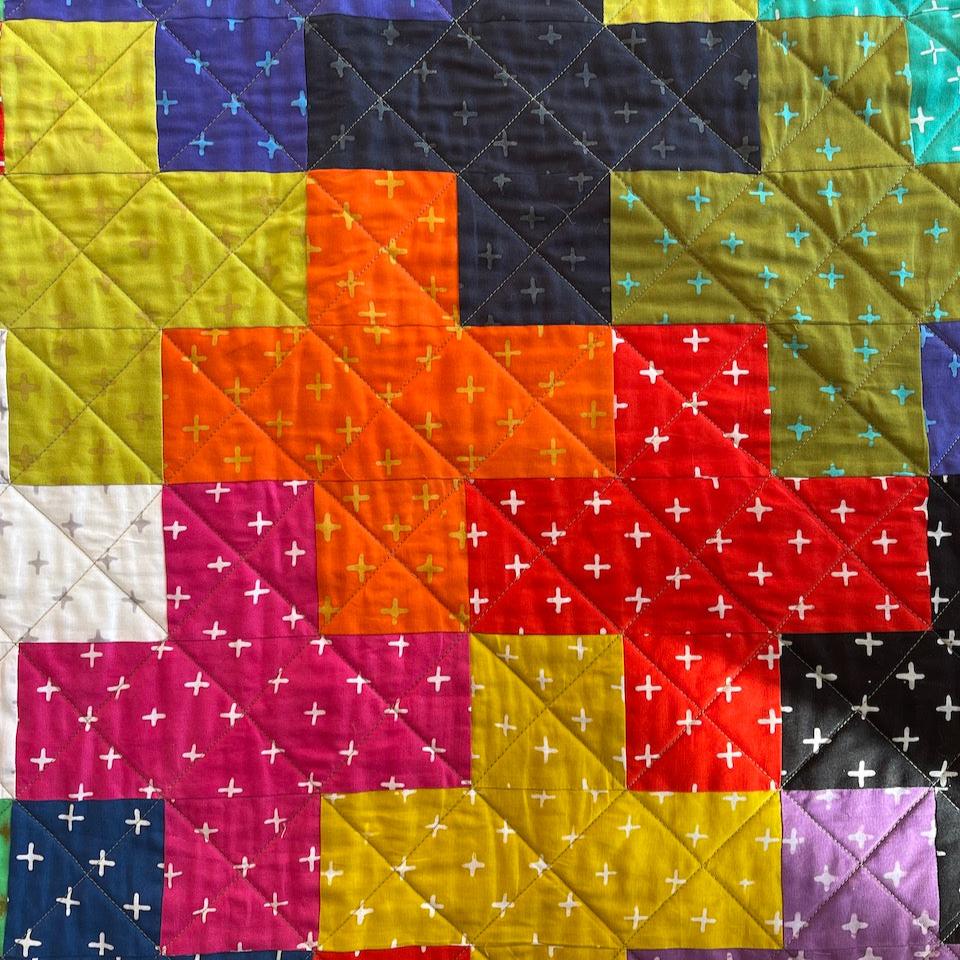 A close up of the Plus quilt showing the plus blocks and the quilting.