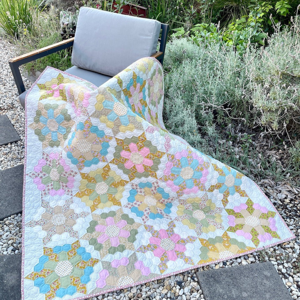The Spring Garden Quilt draped over a chair in the garden