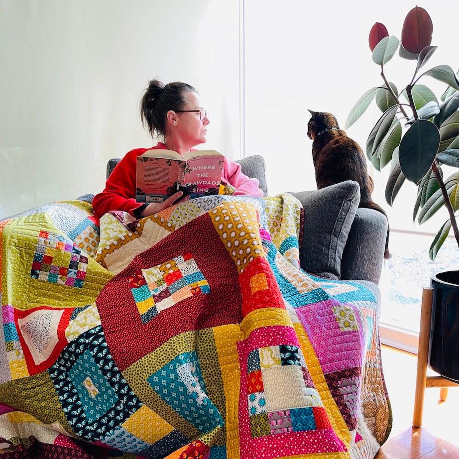 The Squared quilt being used by Chelle (designers sister) while reading. Lucy the cat is keeping her company.
