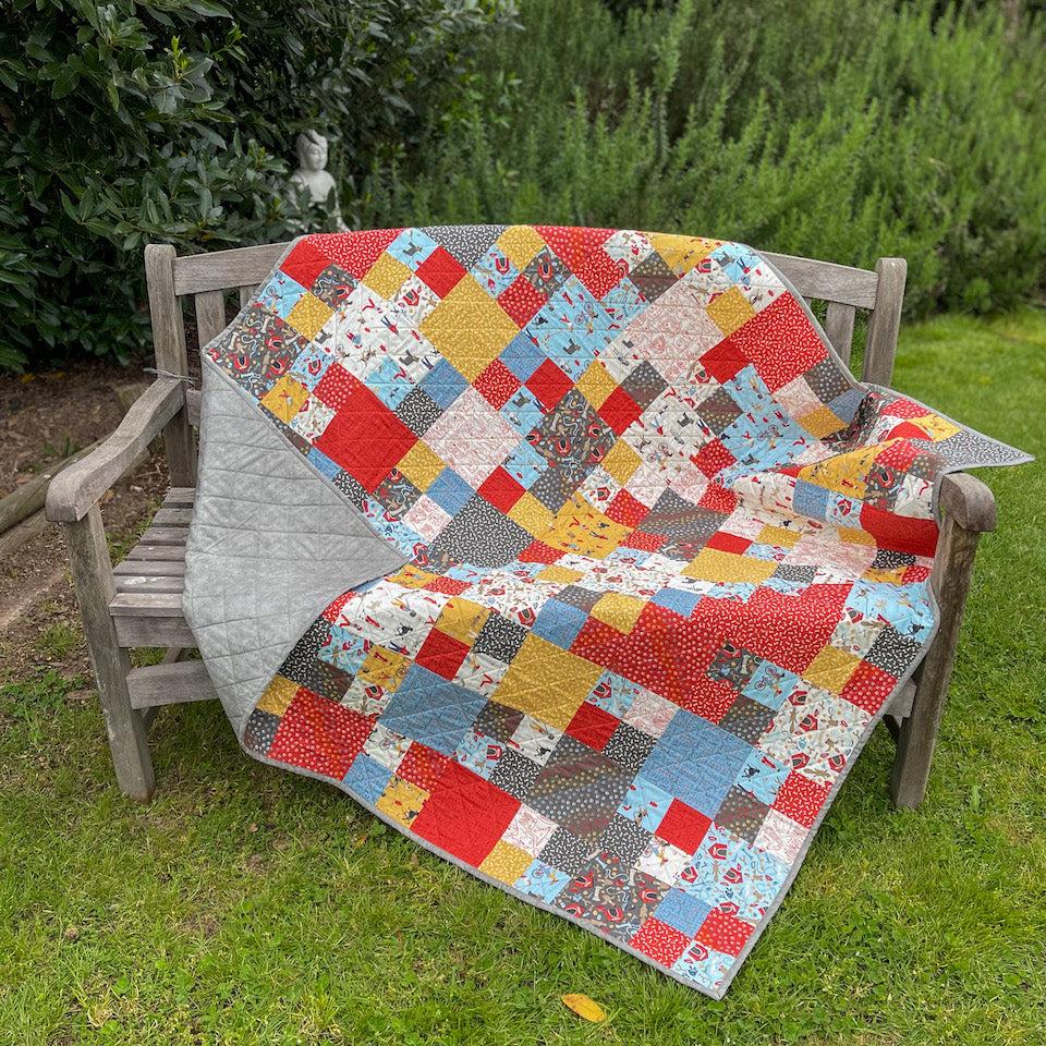 Building Blocks Quilt draped over a bench in the garden