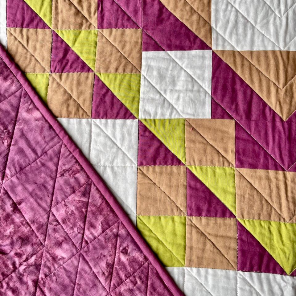 Close up of the Kaleidoscope quilt showing the plum coloured backing