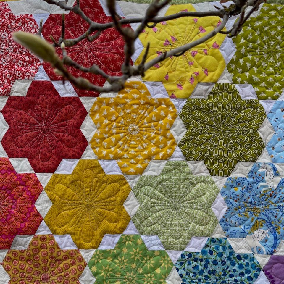 A close up of the Little Blooms blocks showing the rainbow colours and the quilting.