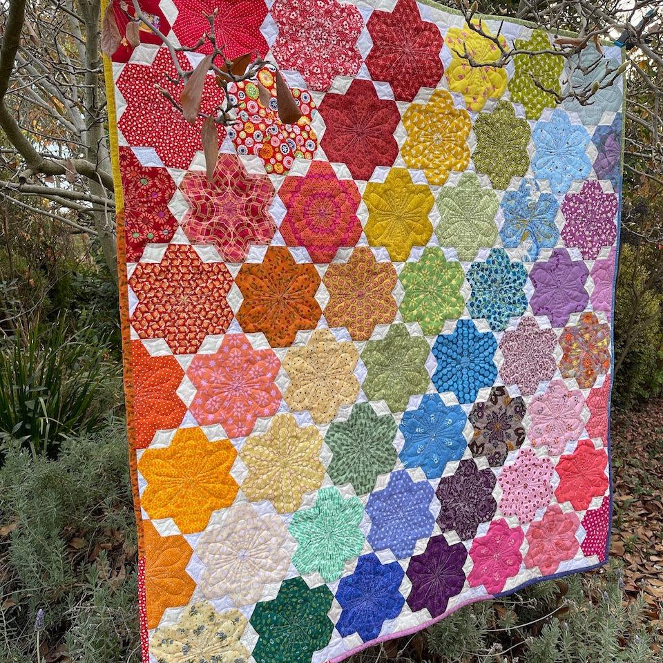 A angled view of the Little Blooms Quilt hanging in a tree.