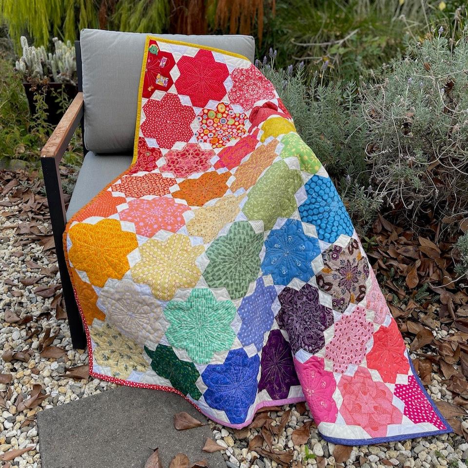 The Little Blooms Quilt draped over a chair in the garden