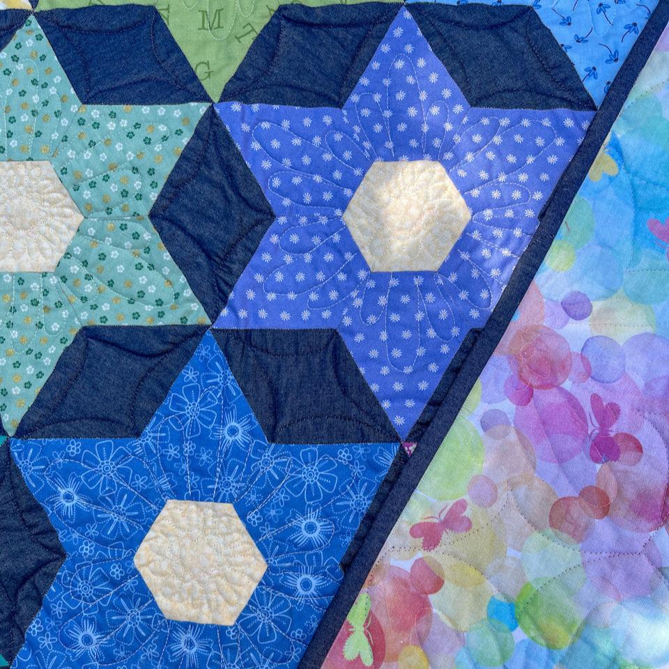 A close up of the Night Blooms quilt showing the quilting and colourful backing fabric.