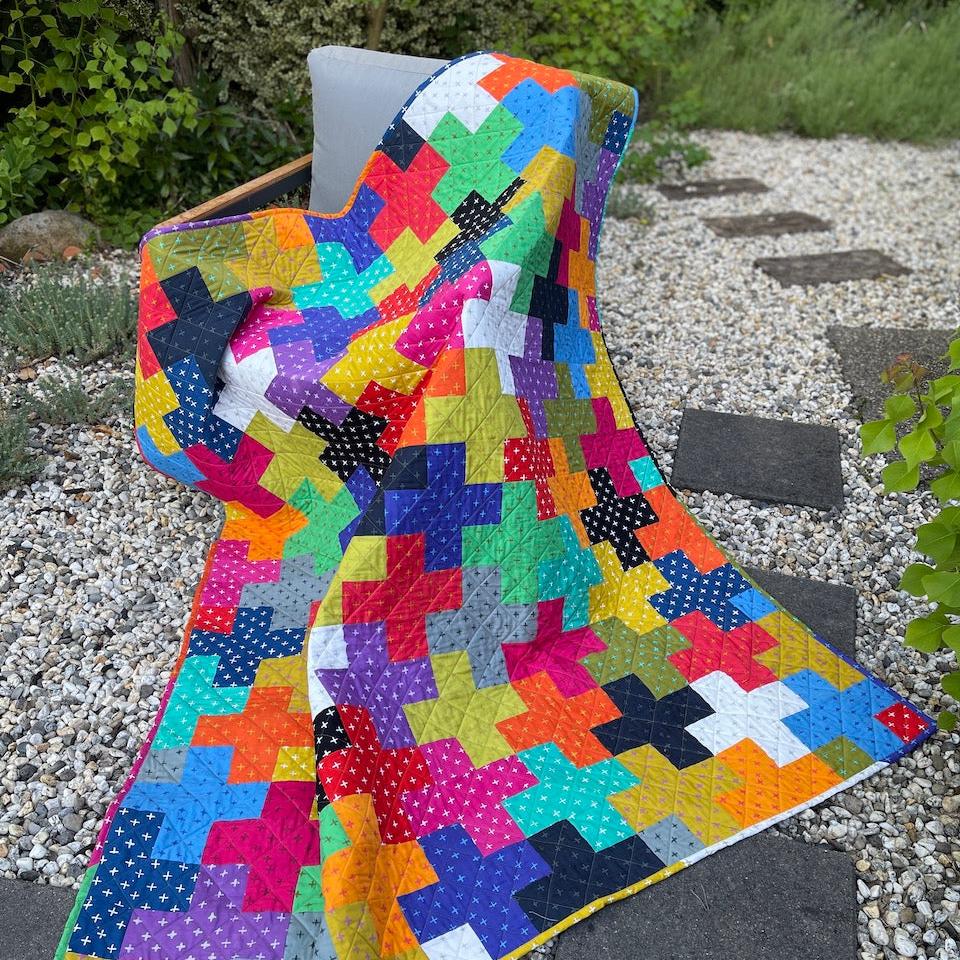 The Plus Quilt draped across a chair in the garden