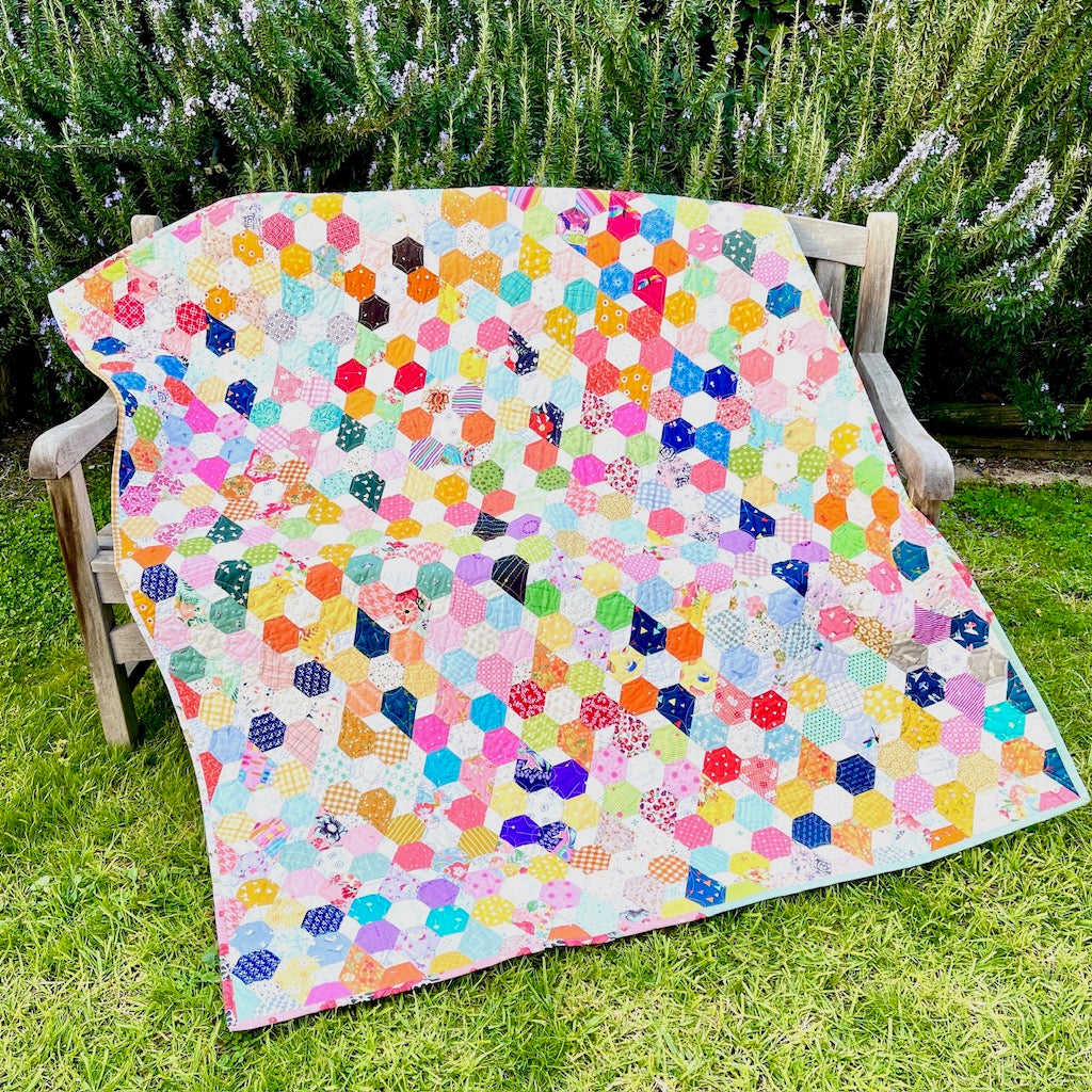 Scrappy Blooms Quilt draped over a Bench in the garden