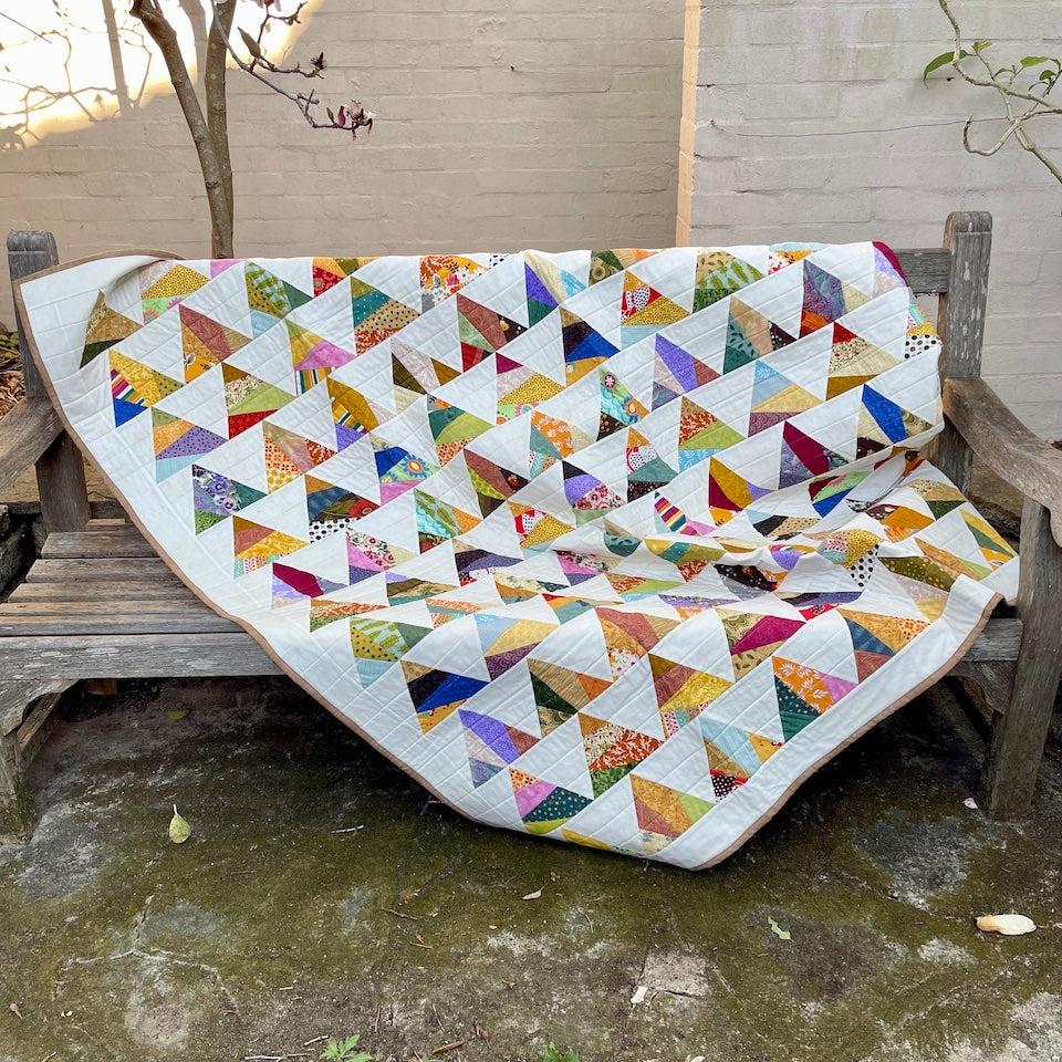 The Triangle Quilt draped over a garden bench